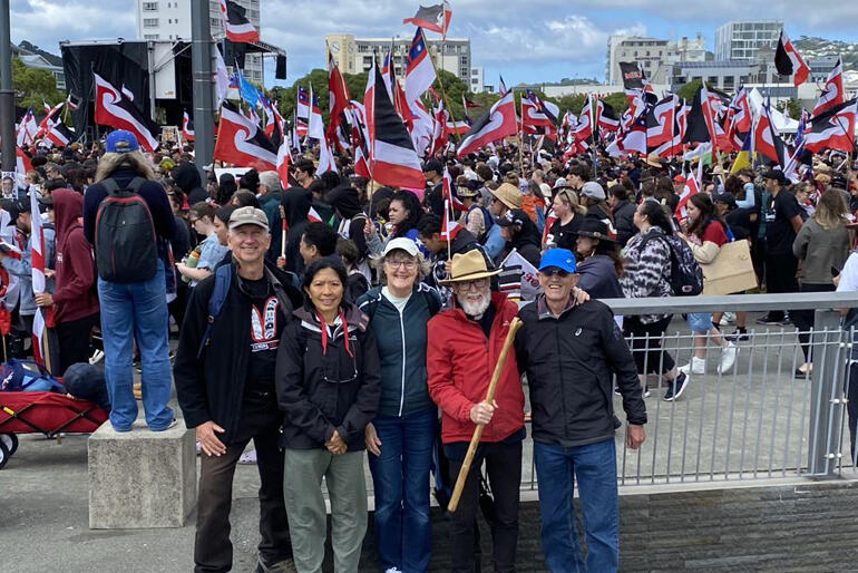 Rev Rob Baigent-Ritchie and friends line up for a photo amongst the festival atmosphere of the Toitū Te Tiriti hikoi on 19 November 2024.