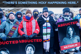 A line of clergy wearing ski jackets and stoles protest ICE abductions