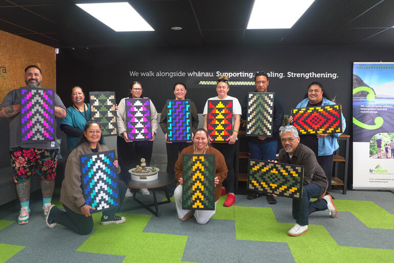 Kaimahi (staff) from Te Whare Ruruhau o Meri line up for a photo with newly woven panels.